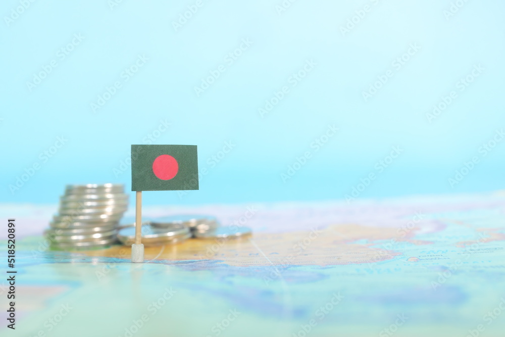 Selective focus of Bangladesh flag in blurry world map with coins. Bangladesh economy and wealth concept.