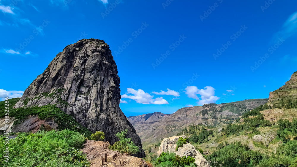 Scenic view on massive volcanic rock formation Roque de Agando in Garajonay National Park on La Gomera, Canary Islands, Spain, Europe. Lava cone of an old volcano. Hiking trail on sunny day in summer