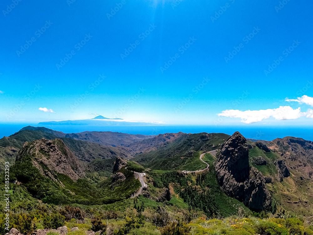 Scenic mountain road with view on massive volcanic rock formation Roque de Agando in Garajonay National Park on La Gomera, Canary Islands, Spain, Europe. View seen from lookout Mirador Morro de Agando