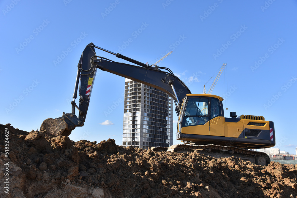 Excavator dig ground at construction site. Construction of multi-storey residential buildings, renovation program. Earthmover on groundwork. Building construction.