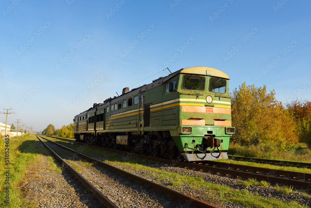 Train locomotive rides on rails. Diesel freight train on railroad in motion. The head of a heavy diesel tractor locomotive for transporting train wagons. Train locomotive rides on rails. Diesel freight train on railroad in motion. The head of a heavy diesel tractor locomotive for transporting train wagons.