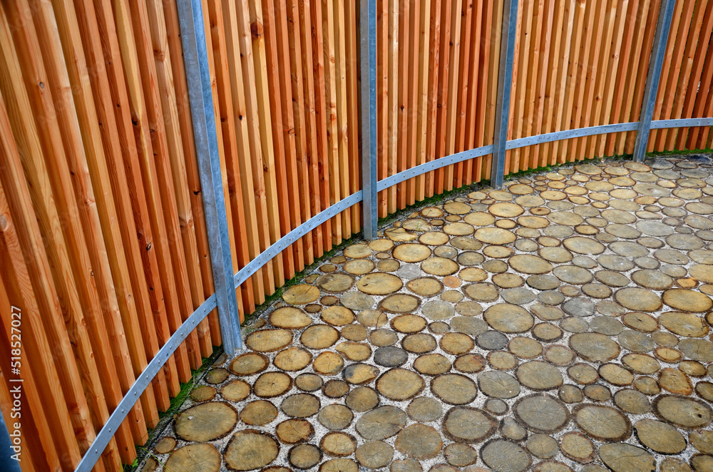 pavement made of acacia logs filled with sand in the joints. fencing made of wood prisms on a