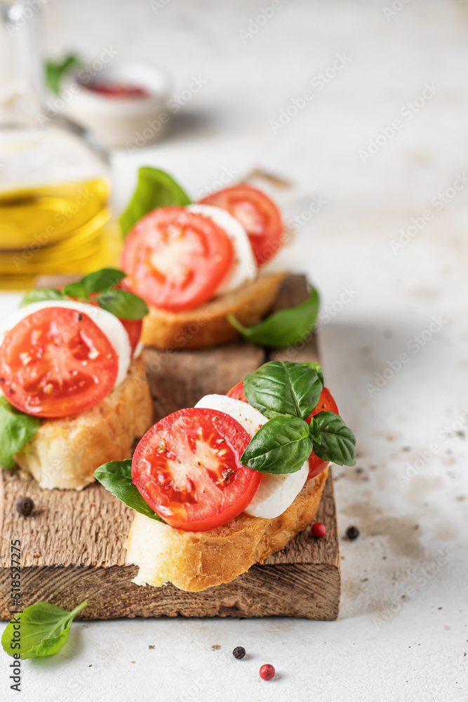 Italian bruschetta with tomatoes, mozzarella and basil on rustic wooden board with ingredients. Copy space Italian bruschetta with tomatoes, mozzarella and basil on rustic wooden board with ingredients. Copy space
