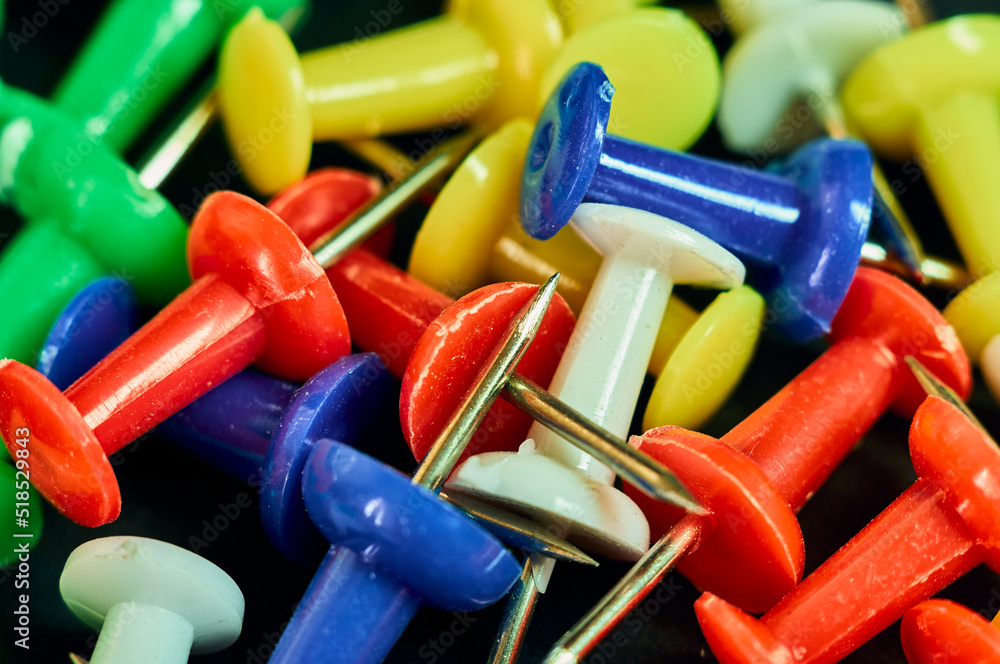 Buttons for attaching paper to a blackboard or wall are photographed in close-up, a sharp metal tip and a plastic handle, many colorful buttons, an office still life Buttons for attaching paper to a blackboard or wall are photographed in close-up, a sharp metal tip and a plastic handle, many colorful buttons, an office still life