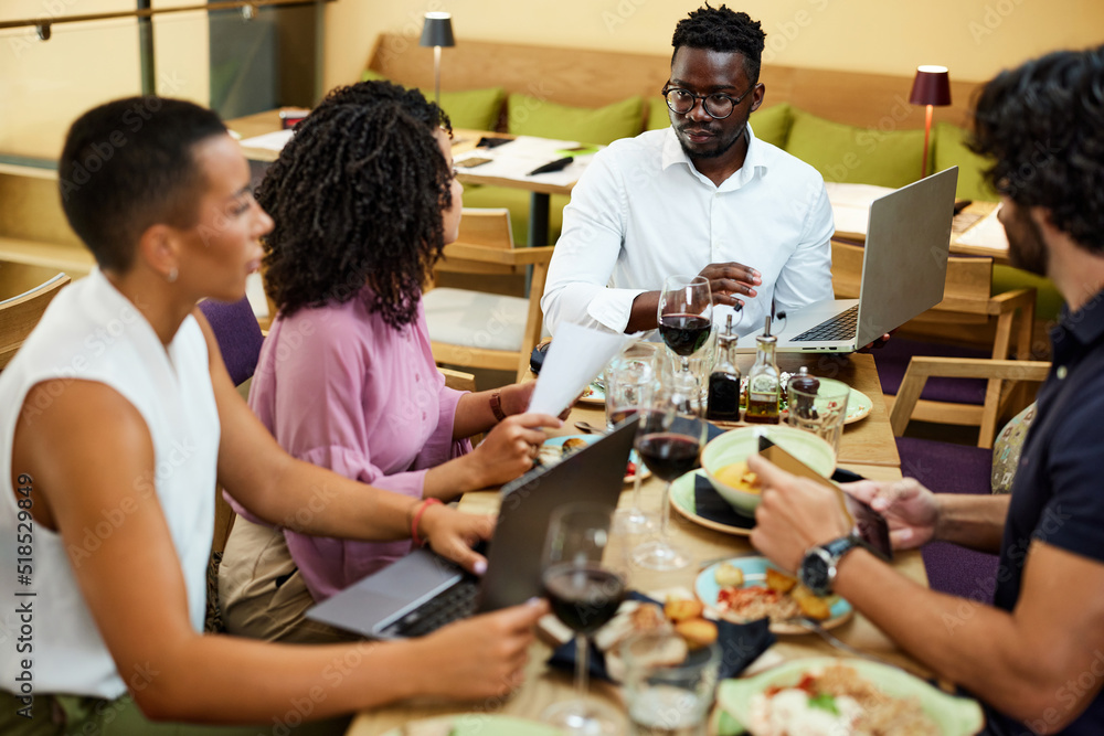 Businesspeople looking at finances report which an African businessman holding. Businesspeople looking at finances report which an African businessman holding.