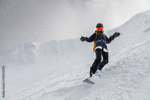 Young stylish girl or woman in motion snowboarding in the mountains