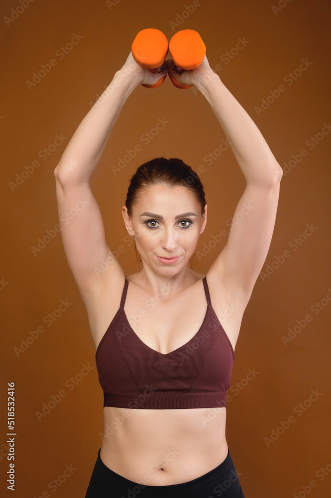 Portrait of a slim athletic woman doing exercises with small dumbbells, studio shot Portrait of a slim athletic woman doing exercises with small dumbbells, studio shot