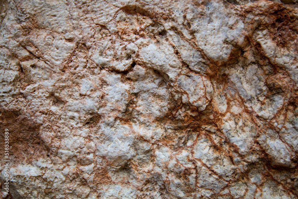 White stone with red flecks. Wavy texture and structure of the stone. There are crystalline inclusions on the surface of the drop. The texture of the rock. White stone with red flecks. Wavy texture and structure of the stone. There are crystalline inclusions on the surface of the drop. The texture of the rock.