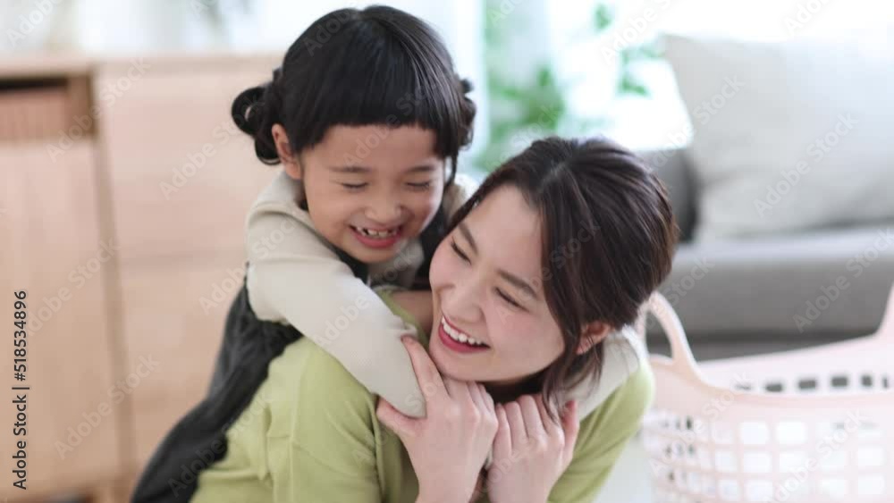洗濯物を畳む母親に抱きつく女の子 洗濯物を畳む母親に抱きつく女の子