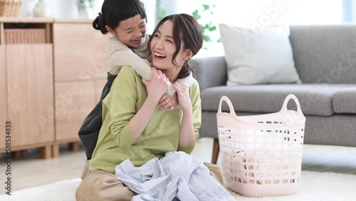 洗濯物を畳む母親に抱きつく女の子
