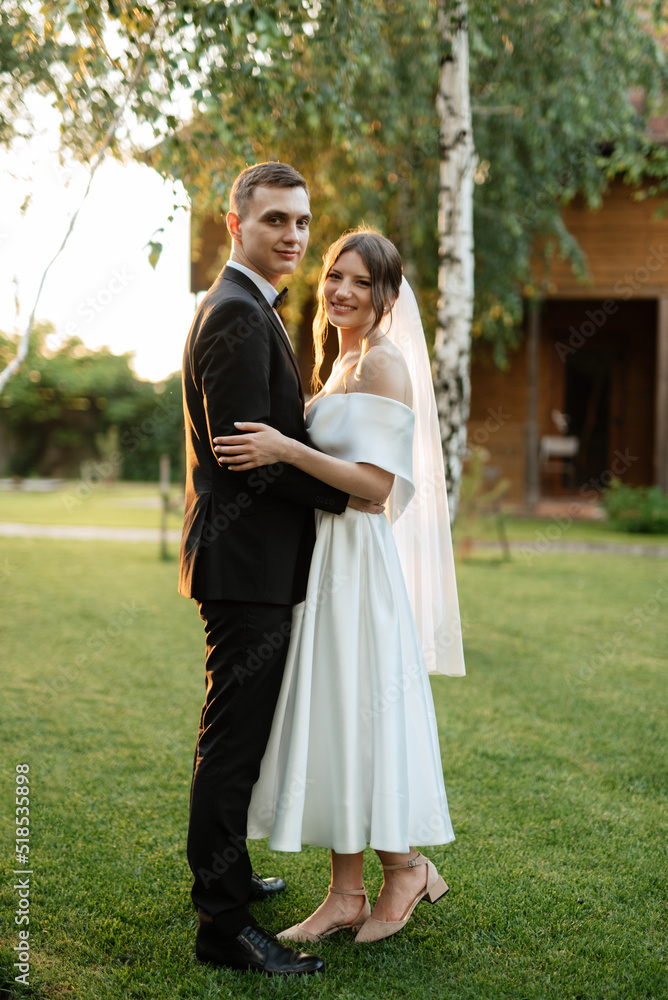 young couple the groom in a black suit and the bride in a white short dress young couple the groom in a black suit and the bride in a white short dress