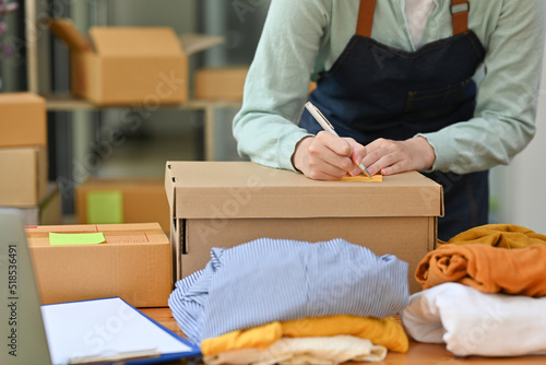 Close up with start up small business owner writing address on parcel box, seller prepare boxes of product for deliver to customer, Online selling or e-commerce concept.