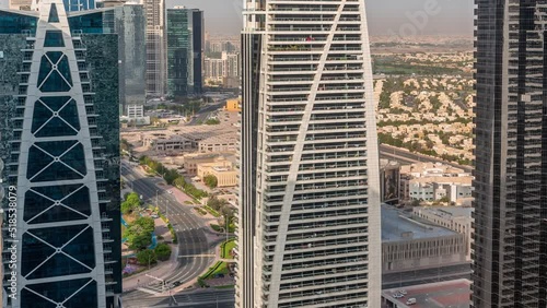 Tall residential buildings at JLT district aerial timelapse, part of the Dubai multi commodities centre mixed-use district. Villa houses and traffic on a background photo