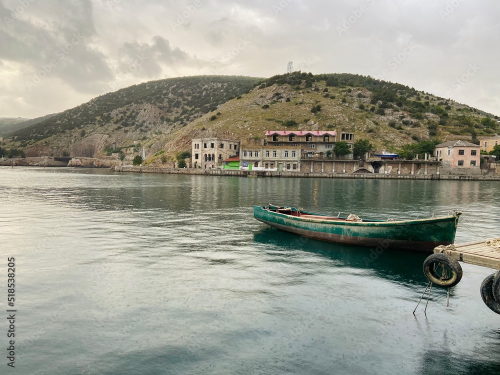 An old wooden boat at the pier on a cloudy rainy day Balaklava Crimea