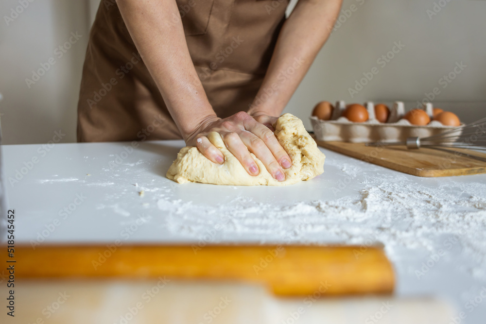 A woman in an apron prepares dough for baking at home. Rolling out and preparing dough for baking. A woman in an apron prepares dough for baking at home. Rolling out and preparing dough for baking.