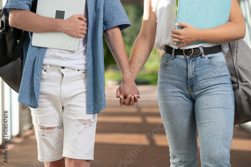 Closeup of students couple holding hands and walking