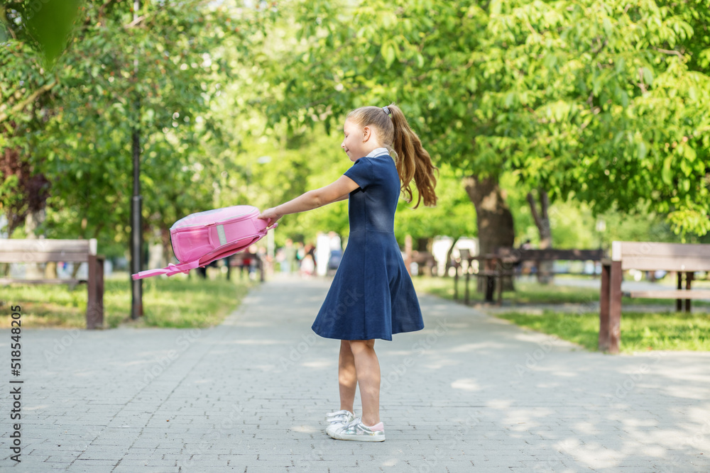 Schoolgirl goes from school and twirls with backpack. Children are having fun. Concept of back to school, learning, friendship and childhood. Schoolgirl goes from school and twirls with backpack. Children are having fun. Concept of back to school, learning, friendship and childhood.