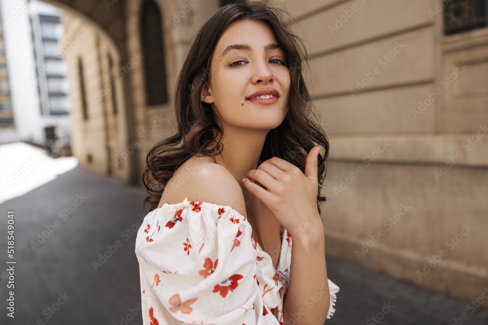 Attractive young caucasian woman posing looking at camera, walking in fresh air during day. Brunette wears summer blouse in warm weather. Concept of enjoying moment Attractive young caucasian woman posing looking at camera, walking in fresh air during day. Brunette wears summer blouse in warm weather. Concept of enjoying moment