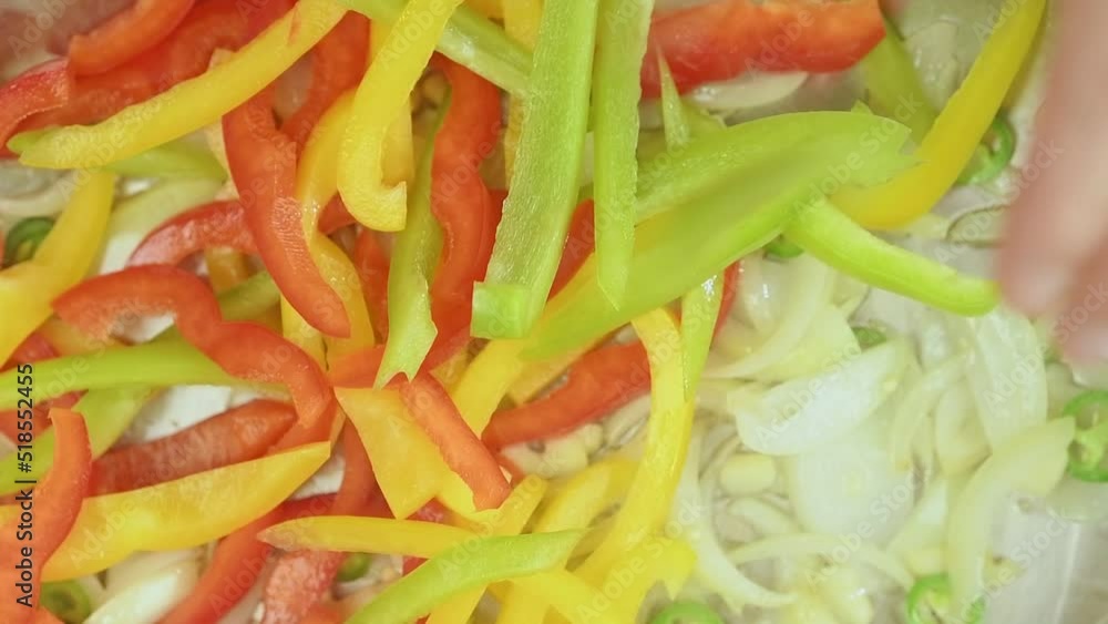 Chef adds sliced green, red and yellow bell peppers into frying pan.
Chef adds sliced green, red and yellow bell peppers into frying pan.
