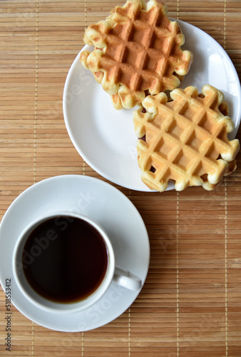 Tea couple with Viennese waffles on a mat. Tea party with waffles. A porcelain cup and saucer on a mat.