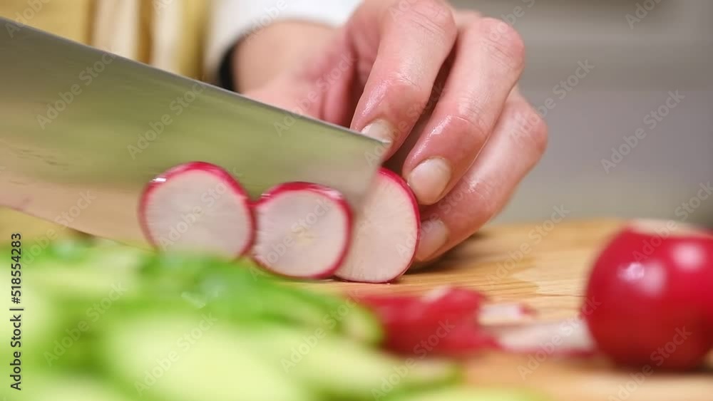 Cutting fresh red radishes on a wooden cutting board, slow motion.
Cutting fresh red radishes on a wooden cutting board, slow motion.
