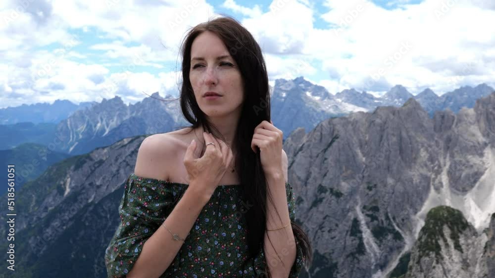 Front view of a young woman in green dress confidently looking in camera and then looking away while camera moves around in slow motion Front view of a young woman in green dress confidently looking in camera and then looking away while camera moves around in slow motion