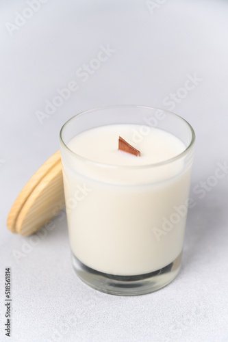 Close-up White Candle in Glass with Wooden Lid on Light Background. Soft Blurry Focus. Place Label