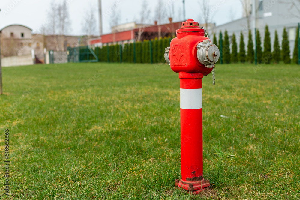Single red fire hydrant on green lawn,near factory.Autumn,spring,summer day.Copy space. Single red fire hydrant on green lawn,near factory.Autumn,spring,summer day.Copy space.