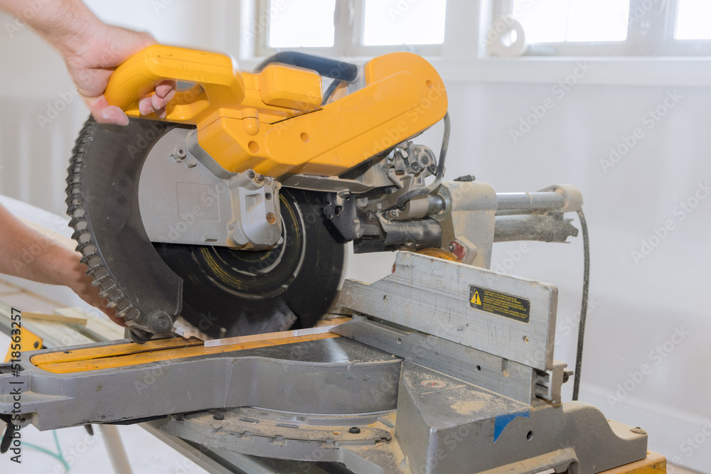 In order to finish the wood moldings baseboard, construction worker uses a circular saw to cut In order to finish the wood moldings baseboard, construction worker uses a circular saw to cut