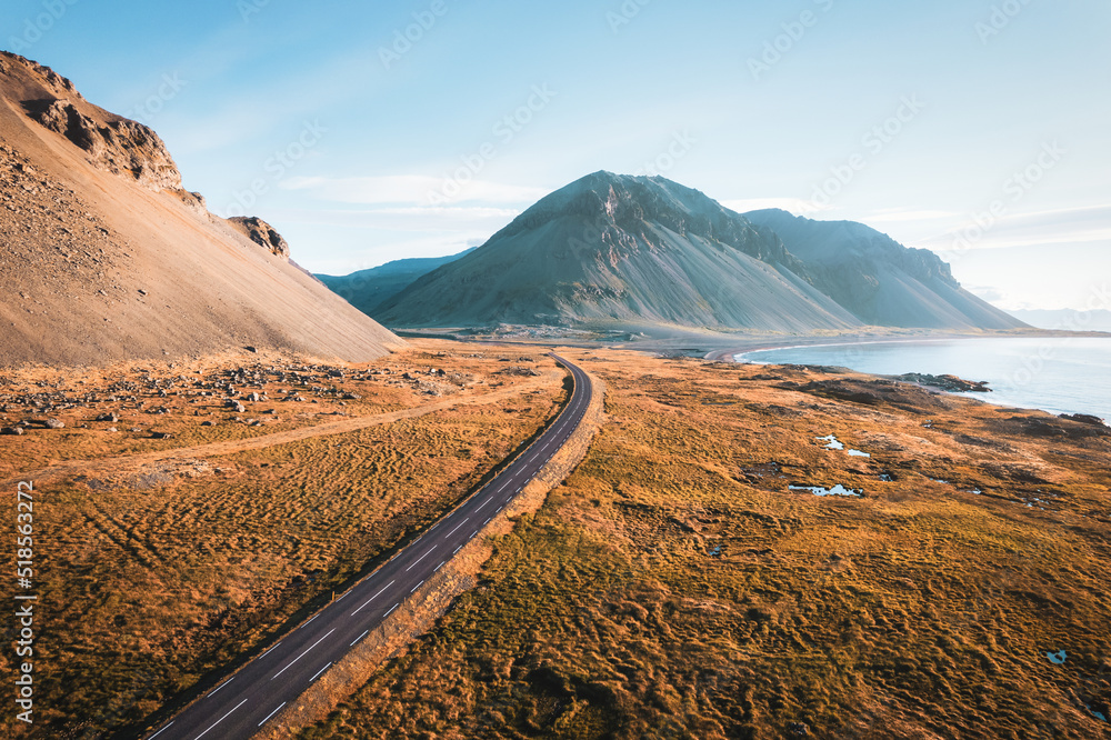 Scenic asphalt road with mountain and golden field on coastline in summer at Iceland