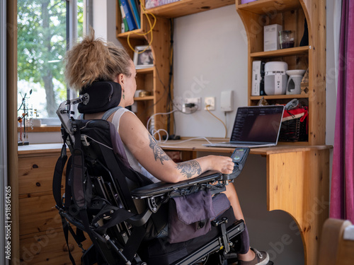 Woman in electric wheelchair working on laptop photo