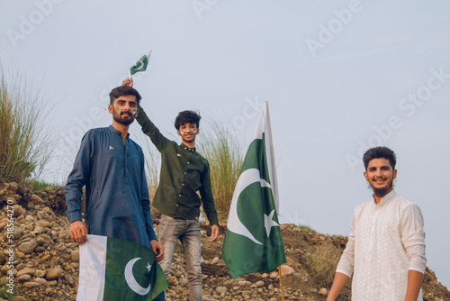 Three Friends celebrating independence Day holding Pakistan Flag, river side, 14th august, photo