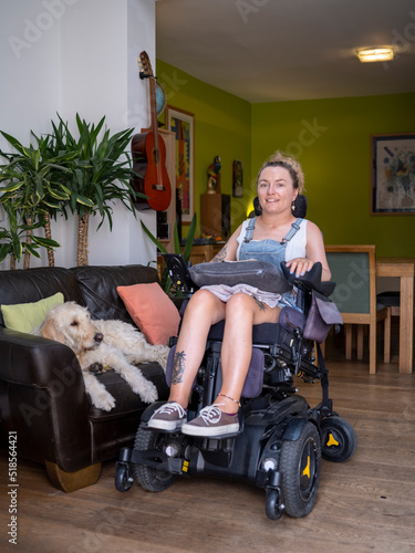 Woman in electric wheelchair with dog in living room