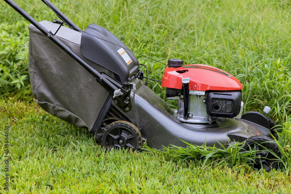 This is a garden care work tool working lawn mower on green lawn with grass being cutting in sunny day