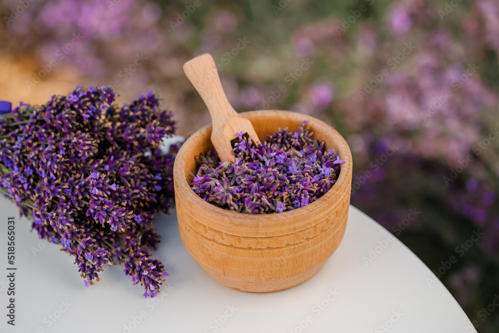 Wooden bowl with dried lavender on field background. Flower herbal tea drink. Aromatherapy, medicine ingredient. Calming beverage Wooden bowl with dried lavender on field background. Flower herbal tea drink. Aromatherapy, medicine ingredient. Calming beverage