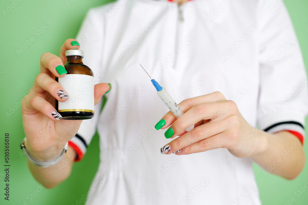 In the hands of a cosmetologist, a syringe and a glass jar with a preparation for a cosmetic procedure. In the hands of a cosmetologist, a syringe and a glass jar with a preparation for a cosmetic procedure.