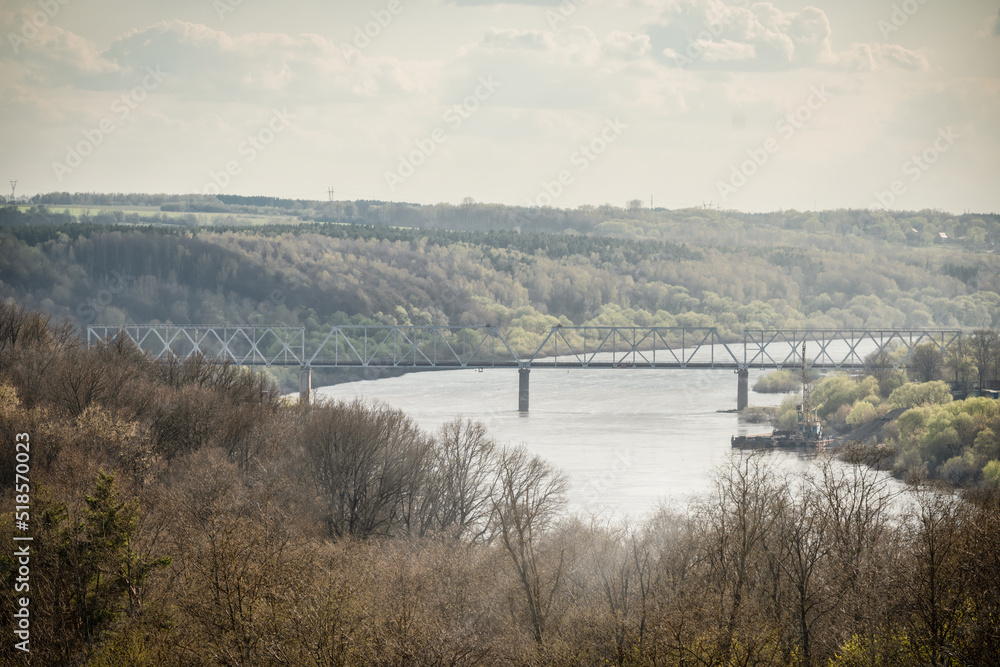 A view from a hill on a bridge over a river against cloudy sky. A view from a hill on a bridge over a river against cloudy sky.