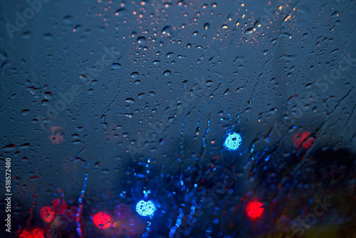 Light of the traffic and car on a rainy night through the windshield