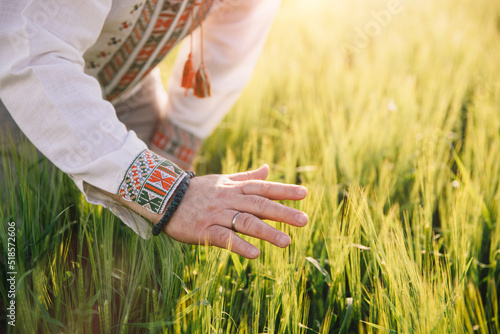A man in Ukrainian embroidery touches wheat at sunset. Concept of preservation of Ukrainian grain, blockade of ports, world hunger and crisis