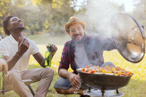 Two guys are preparing a barbecue for friends. The joy of grilling together in nature.