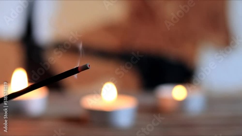 close up of incense burning with smoke and candles 