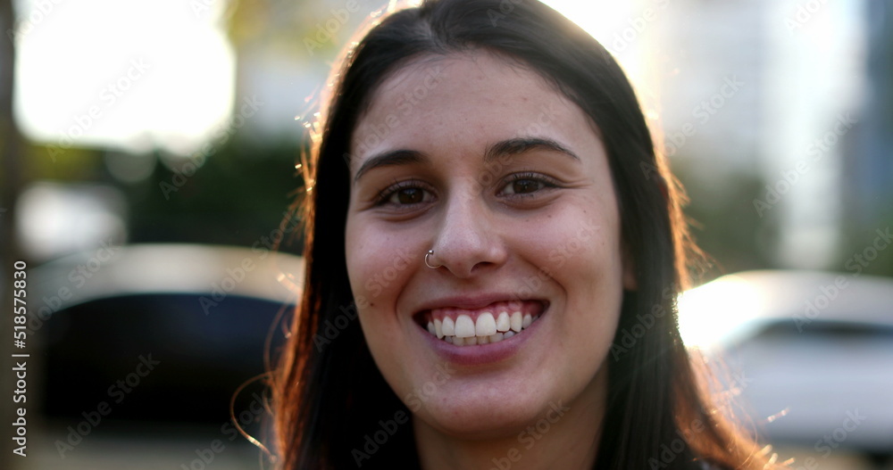 Portrait of millennial girl smiling at camera outside. Young 20 year old woman Portrait of millennial girl smiling at camera outside. Young 20 year old woman