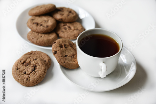Tea pair and oatmeal cookies with chocolate on a white background. Delicious lunch with tea and sweet cookies. Porcelain tea set with a hot drink.