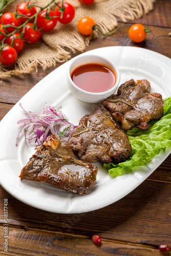 skewers of mutton flesh and tomato sauce with red onion on plate on wooden table
