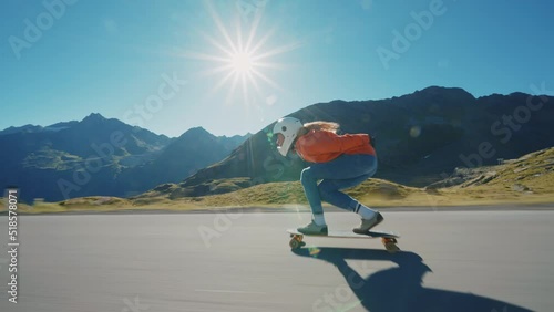 Cinematic downhill longboard session. Young woman skateboarding and making tricks between the curves on a mountain pass. Concept about extreme sports and people photo