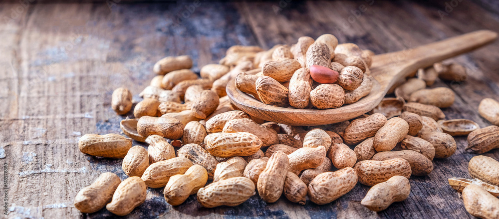 Fototapeta premium Dried peanuts or nuts on wooden background.Peanut shells on a wooden spoon