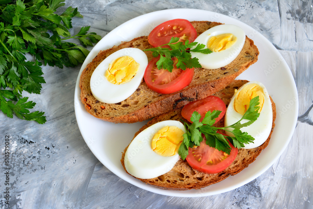 bread slices with boiled eggs and tomatoes on plate decorated with parsley, close-up bread slices with boiled eggs and tomatoes on plate decorated with parsley, close-up