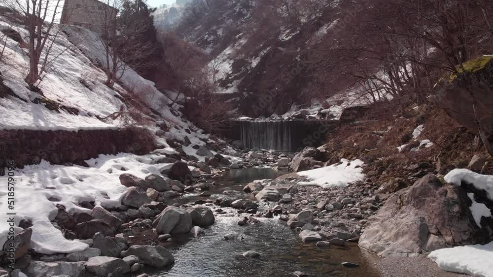 Aerial view of a river and waterfall in Fukui, surrounded by snow Aerial view of a river and waterfall in Fukui, surrounded by snow