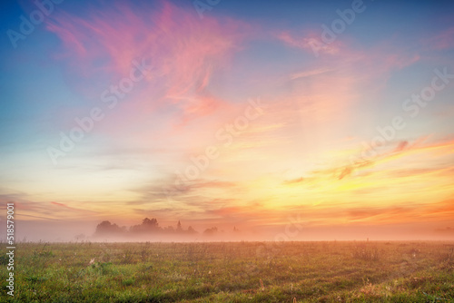 Bright yellow-pink sky before dawn in a foggy field. A natural landscape.  © Denis Gavrilov Photo