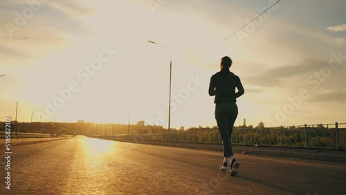 athletic woman is running outdoors in morning, training in sunrise for keeping fit and good health